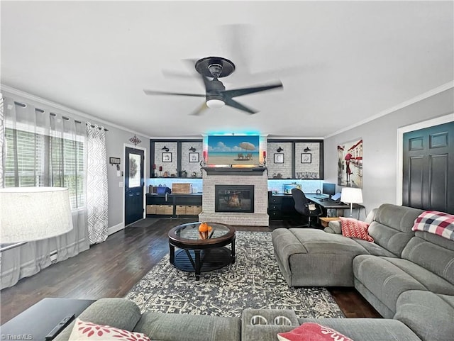 living room with ornamental molding, ceiling fan, wood finished floors, and a fireplace