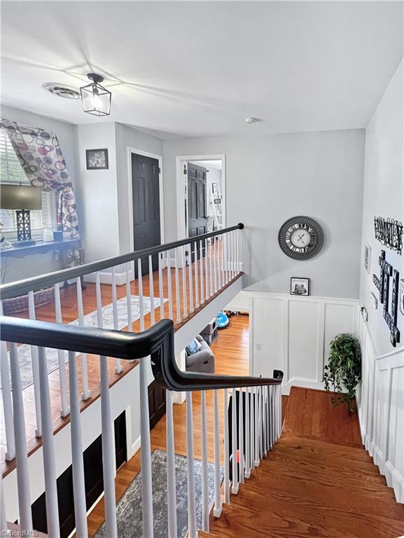 staircase featuring wood finished floors and a wainscoted wall