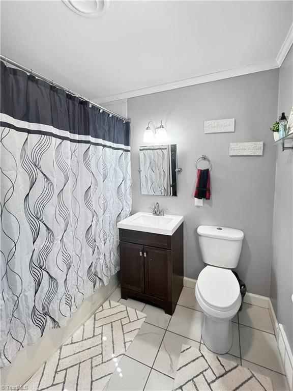 full bathroom with vanity, ornamental molding, curtained shower, and toilet