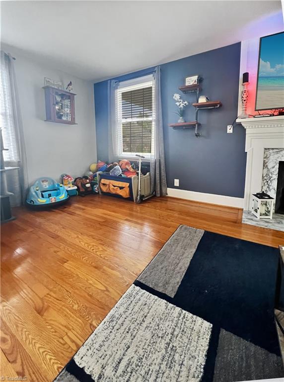 bedroom featuring baseboards, wood finished floors, and a high end fireplace