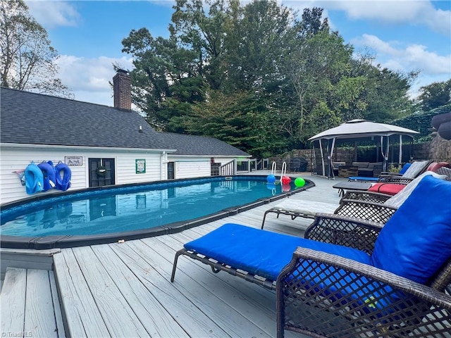 pool featuring a gazebo, a wooden deck, an outdoor hangout area, and fence