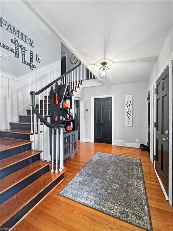 foyer entrance with baseboards, wood finished floors, and stairway