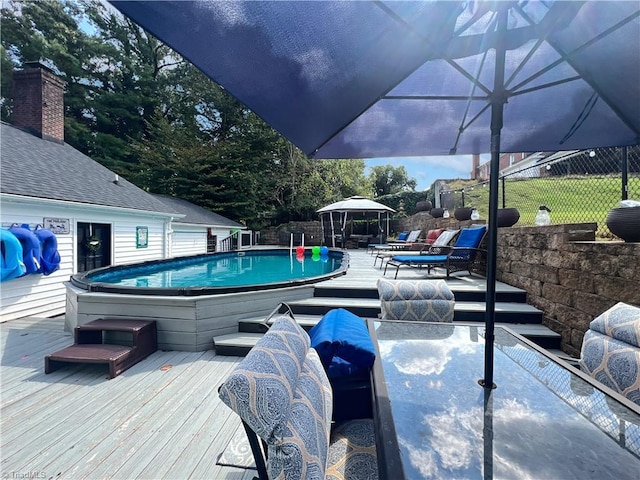 outdoor pool with fence, a wooden deck, and a jacuzzi
