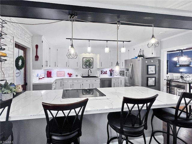 kitchen with decorative backsplash, appliances with stainless steel finishes, a sink, white cabinets, and ornamental molding