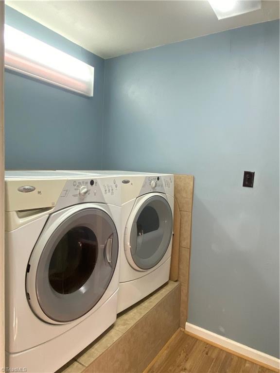 laundry area with washing machine and clothes dryer and light hardwood / wood-style flooring