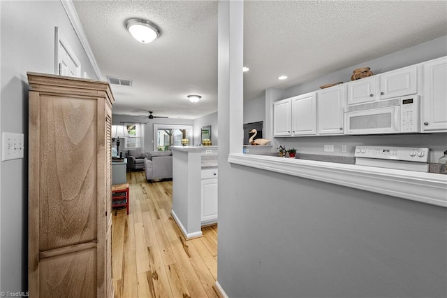 kitchen featuring ceiling fan, stove, light hardwood / wood-style floors, and white cabinetry