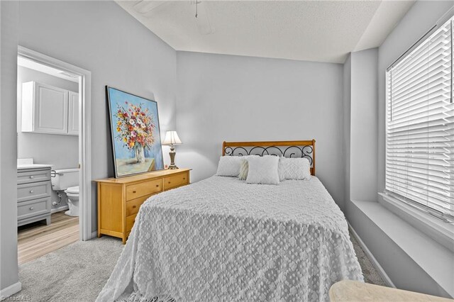 bedroom featuring connected bathroom, light wood-type flooring, and ceiling fan