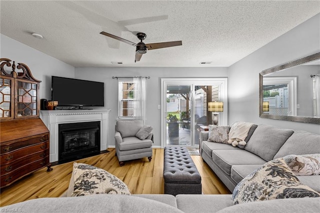 living room featuring ceiling fan, a textured ceiling, and light hardwood / wood-style floors