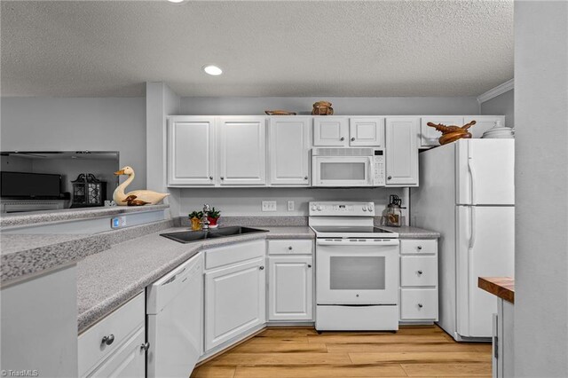 kitchen with white appliances, light wood-type flooring, a textured ceiling, white cabinets, and sink