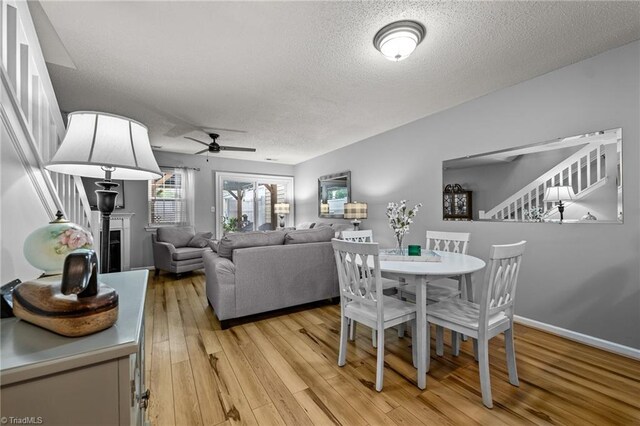 dining area with light hardwood / wood-style flooring, a textured ceiling, and ceiling fan