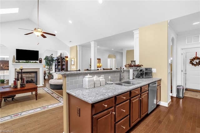 kitchen featuring a sink, dishwasher, open floor plan, ceiling fan, and a peninsula