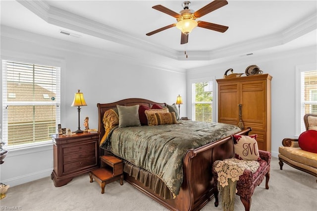 bedroom featuring a raised ceiling, light colored carpet, ornamental molding, ceiling fan, and baseboards