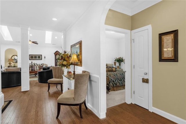 hallway with hardwood / wood-style flooring, crown molding, and a skylight