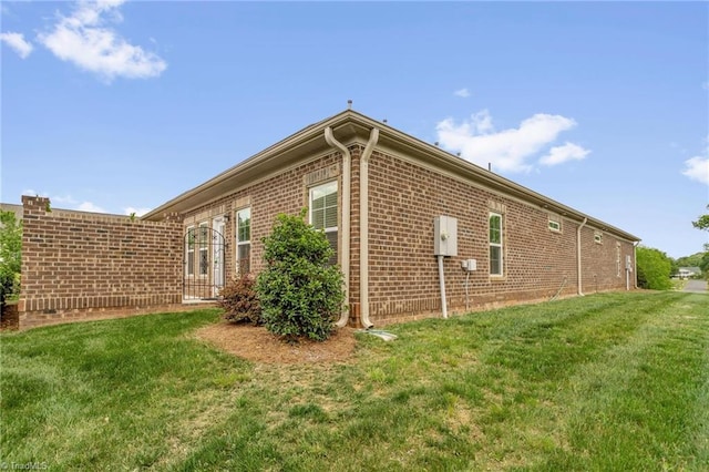 view of property exterior with a lawn and brick siding