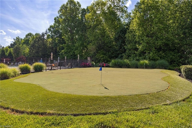 surrounding community with fence and a putting area