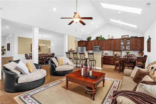 living area with ornate columns, light wood finished floors, high vaulted ceiling, ceiling fan, and recessed lighting