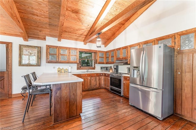 kitchen with beam ceiling, kitchen peninsula, dark wood-type flooring, stainless steel appliances, and a kitchen bar