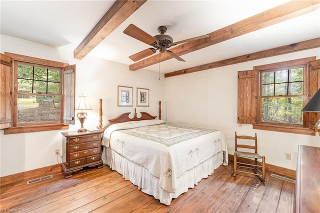 bedroom featuring baseboards, hardwood / wood-style flooring, visible vents, and beam ceiling