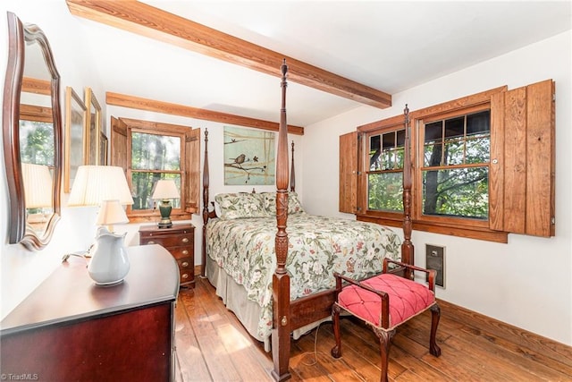 bedroom with beamed ceiling and light hardwood / wood-style flooring