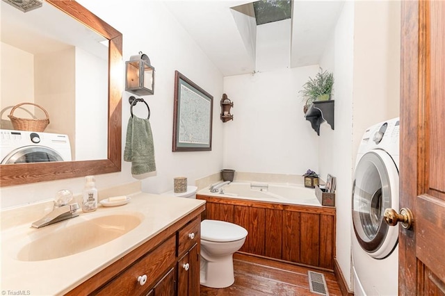 bathroom featuring wood-type flooring, washer / clothes dryer, vanity, and a bath