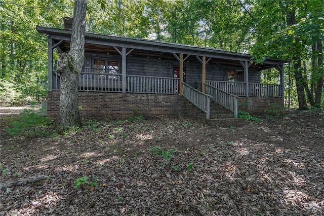 exterior space featuring a chimney, covered porch, and stairs