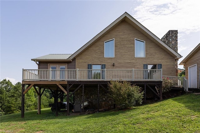 back of house featuring metal roof, a lawn, a chimney, and a wooden deck