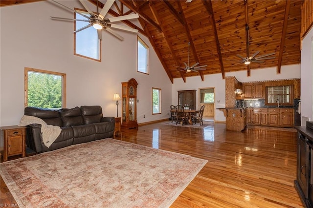 living area with wooden ceiling, light wood-style flooring, baseboards, and beamed ceiling