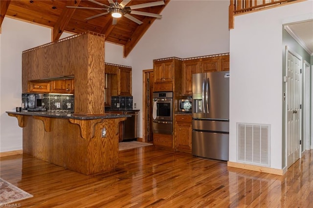 kitchen featuring stainless steel appliances, brown cabinets, visible vents, and a peninsula