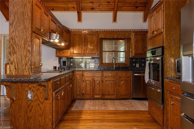 kitchen featuring a sink, stainless steel appliances, brown cabinets, and under cabinet range hood