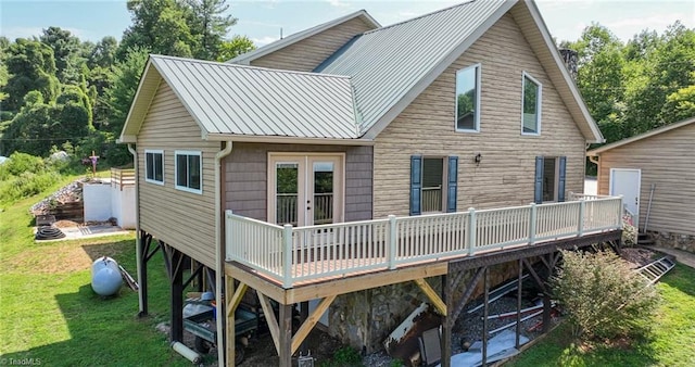 back of property featuring metal roof, a lawn, and a wooden deck