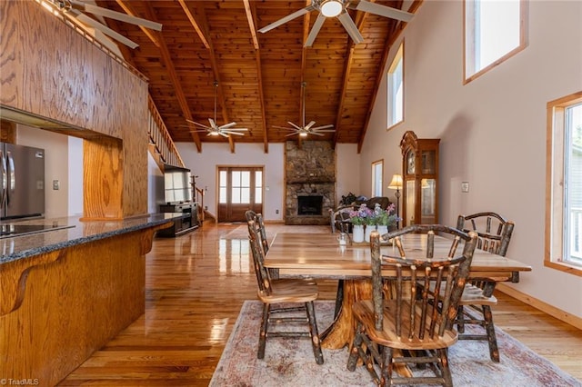 dining space featuring a fireplace, light wood-type flooring, wooden ceiling, beamed ceiling, and baseboards