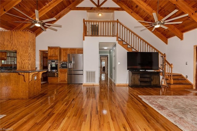 kitchen with visible vents, appliances with stainless steel finishes, brown cabinets, wood finished floors, and open floor plan