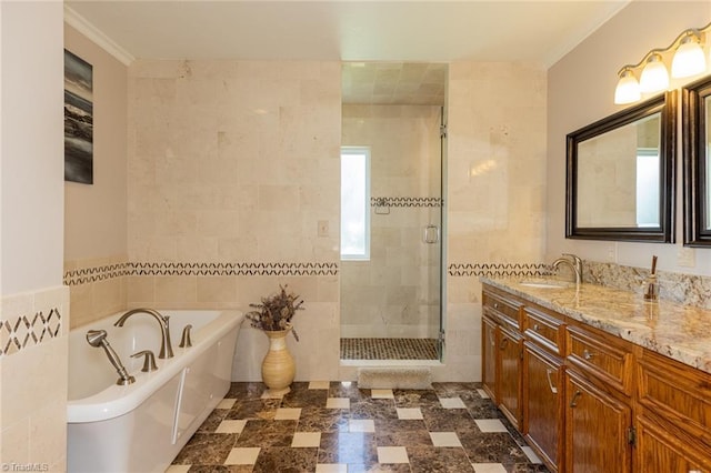 bathroom featuring a stall shower, a soaking tub, tile walls, and vanity