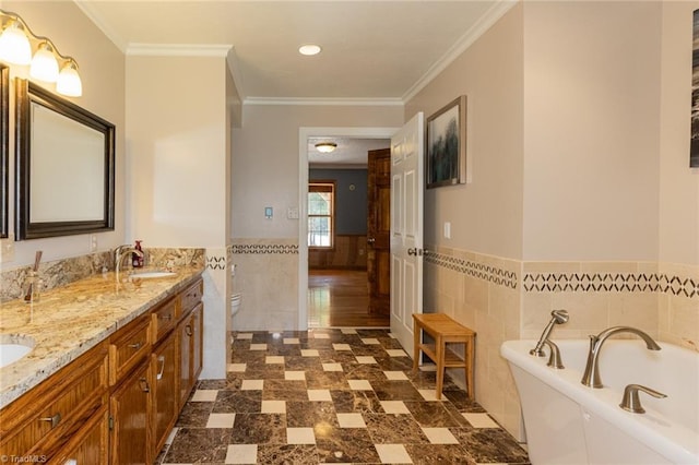 bathroom with double vanity, a wainscoted wall, a sink, a bathtub, and tile walls