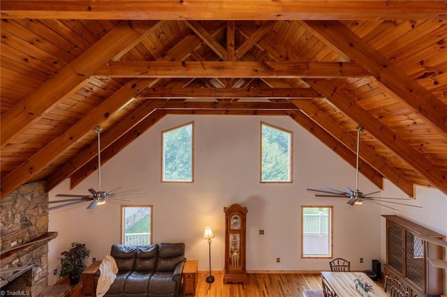 unfurnished living room featuring vaulted ceiling with beams, a stone fireplace, plenty of natural light, and wood finished floors