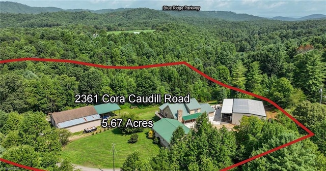 birds eye view of property with a mountain view and a wooded view