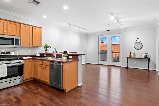 kitchen with a peninsula, dark wood-type flooring, visible vents, ornamental molding, and appliances with stainless steel finishes