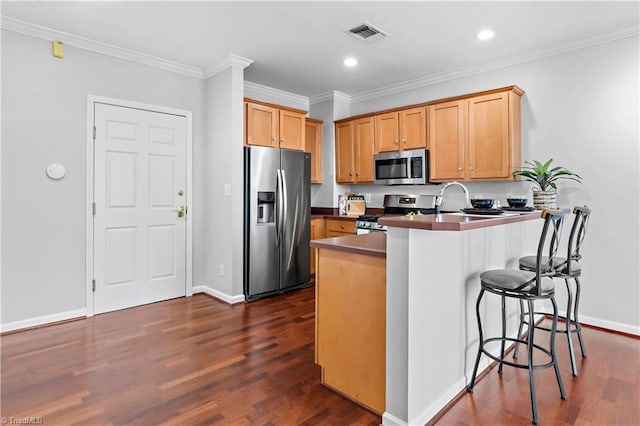 kitchen featuring a peninsula, visible vents, appliances with stainless steel finishes, dark wood finished floors, and crown molding