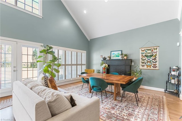 office space with hardwood / wood-style floors, french doors, high vaulted ceiling, and a brick fireplace