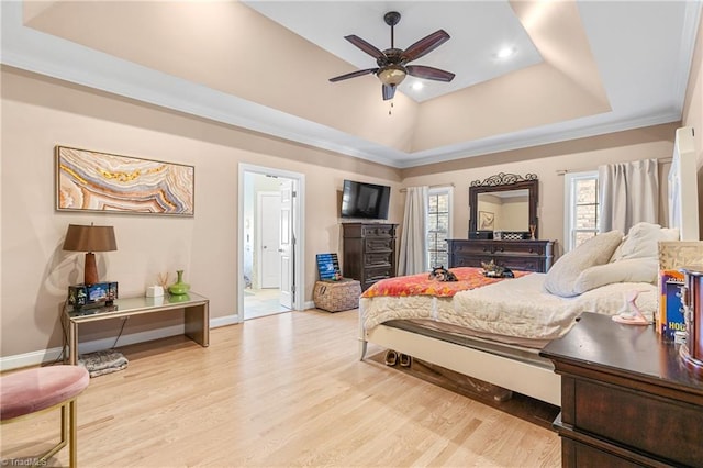 bedroom featuring ornamental molding, a tray ceiling, ceiling fan, light hardwood / wood-style flooring, and connected bathroom