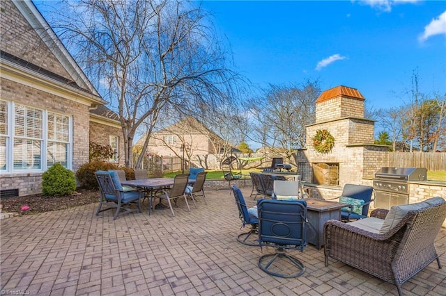 view of patio with an outdoor fireplace and a grill