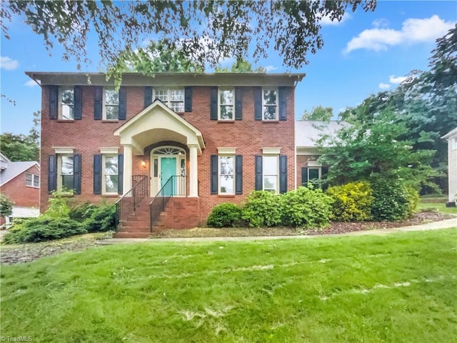 colonial-style house featuring a front yard and brick siding