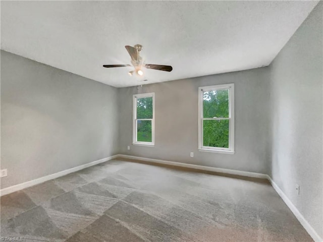 carpeted empty room featuring ceiling fan and baseboards