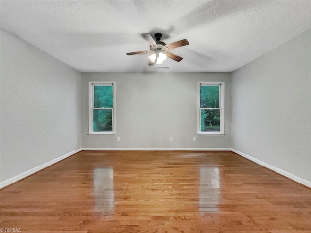 spare room with a textured ceiling, baseboards, and wood finished floors