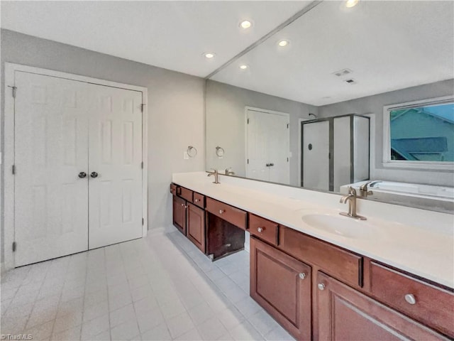 bathroom featuring double vanity, a shower stall, a sink, and recessed lighting