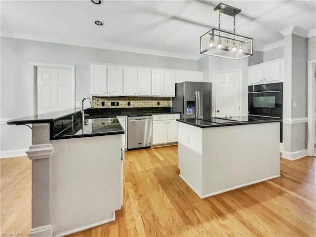 kitchen featuring decorative light fixtures, black appliances, a center island, sink, and light hardwood / wood-style floors