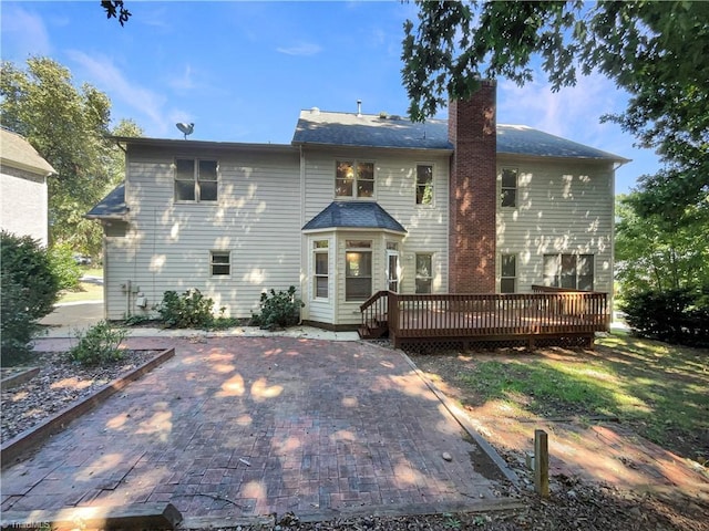 back of property with a deck, a patio, and a chimney