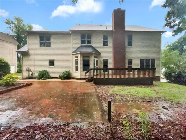 back of property with a chimney and a wooden deck