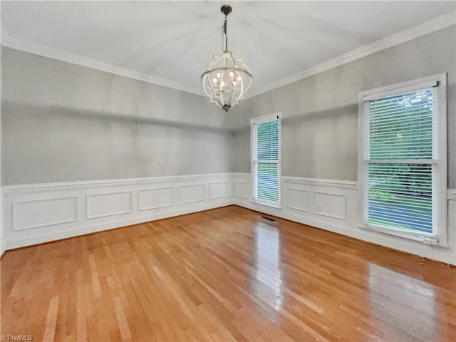 unfurnished room featuring a wainscoted wall, a chandelier, wood finished floors, and ornamental molding