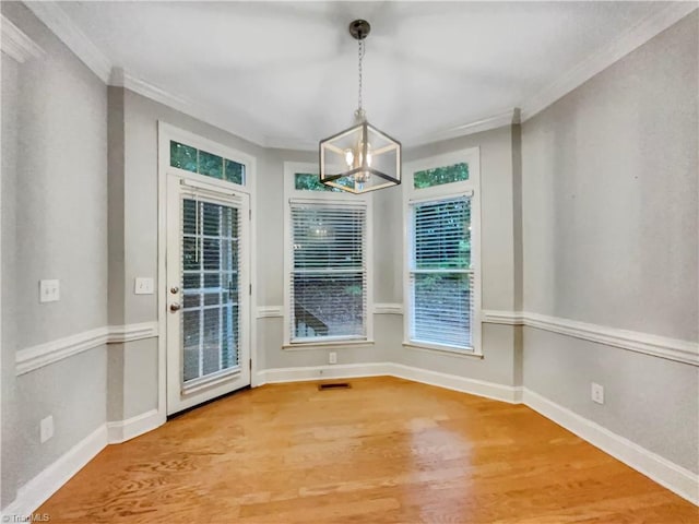 unfurnished dining area with baseboards, ornamental molding, and wood finished floors